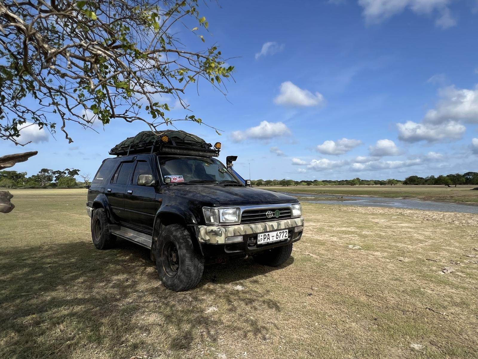 Kelaya Photography safari jeep parked by a waterhole in open park country